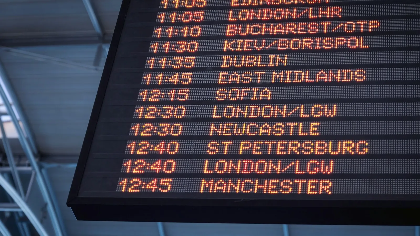 An airport departure board listing multiple flights and departure times, the kind travelers watch when a delay is announced.